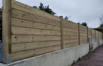 Réalisation d’une clôture sur muret en pin classe IV. Pose sur embases scellées.